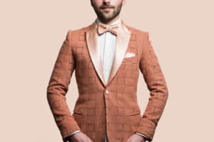 Blazer sur-mesure Monsieur List en laine rose saumon brodé main quadrillage coton rose et noir. Chemise et pochette de costume sur-mesure Monsieur List en coton brodé quadrillage coton blanc. Noeud papillon sur-mesure Monsieur List satin de soie rose saumon brodé chevrons soie rose. Fait en France. Photographie de Marcel Kultscher.